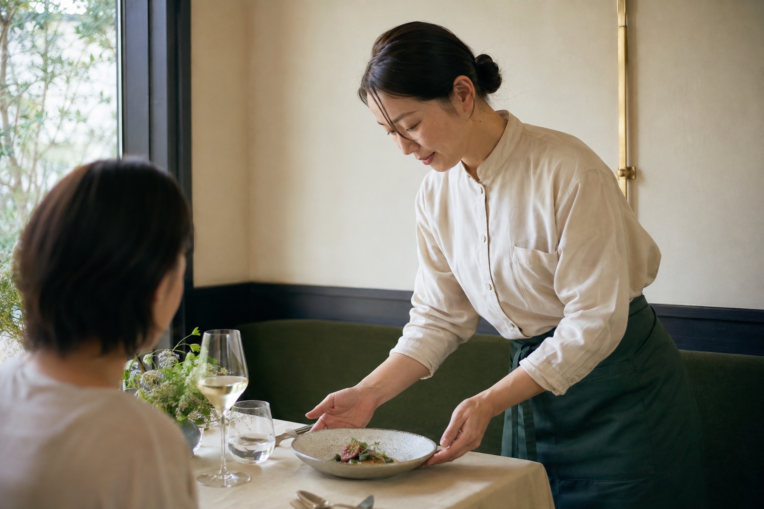 小さなテーブルへ料理を運ぶサービス風景